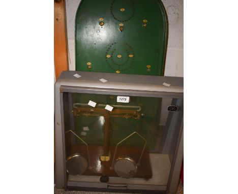 A Bagatelle board; a set of chemist's balance scales, glass case (2)