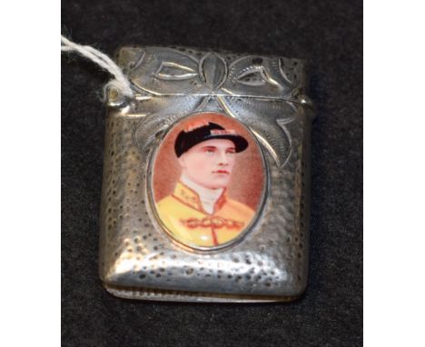 A silver coloured metal rounded rectangular vesta case, applied with an oval enamel panel printed with a jockey 