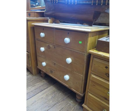 An Edwardian pine chest of drawers with two short and two long drawers, with ceramic handles and turned feet, 84 cm wide, 45 