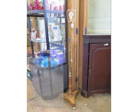 A brass and crossbanded maple standard lamp, previously a pole screen, on brass paw feet 