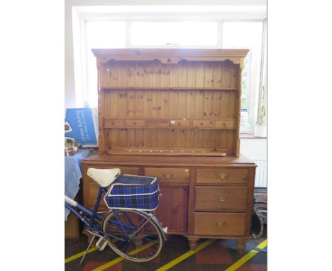 A pine dresser with associated rack, the rack with trinket drawers, 137 cm wide, over a dresser with seven drawers around a c