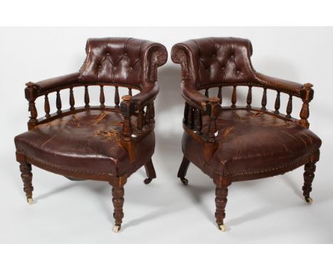 A pair of Victorian leather upholstered tub armchairs, with button stud decoration to back, raised on original ceramic castor