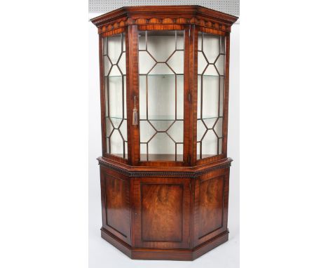 A reproduction George III style mahogany glazed display cabinet, of canted D-section, with geometric astragals enclosing two 