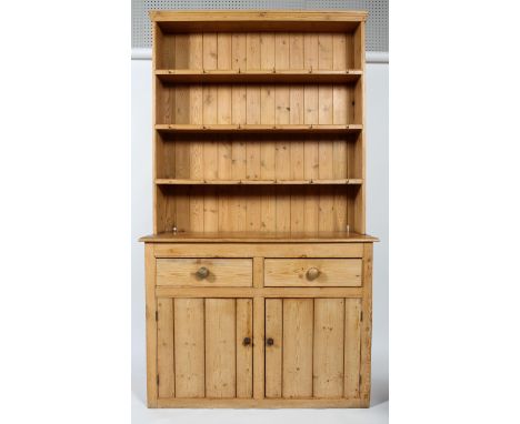 A pine kitchen dresser, with three fixed shelves above a two drawer and two cupboard panelled door base, enclosing a shelf, t