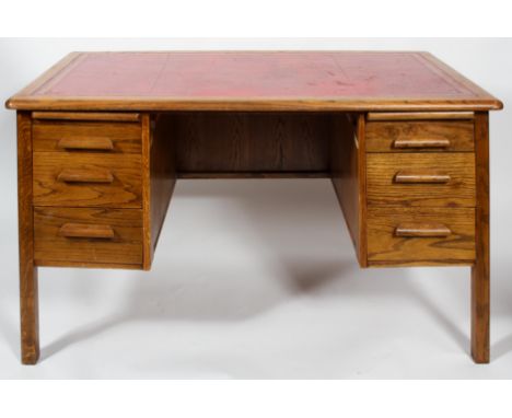 A mid 20th century vintage golden oak twin pedestal desk having a red leather top, graduating drawers to either side, all rai
