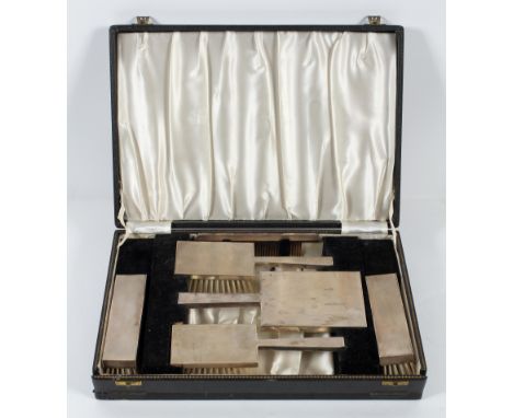 An Art deco style silver mounted dressing table set, comprising brushes, hand mirror and comb, each with engine turned decora