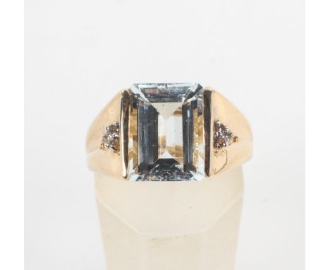 A yellow metal ring principally set with a rectangular cut colourless beryl (goshenite) and finished with diamond set shoulde