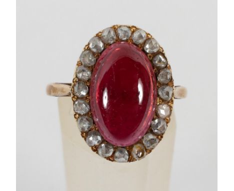 A yellow metal cluster ring principally set with a cabochon cut garnet and surrounded by rose cut diamonds. No hallmark - tes
