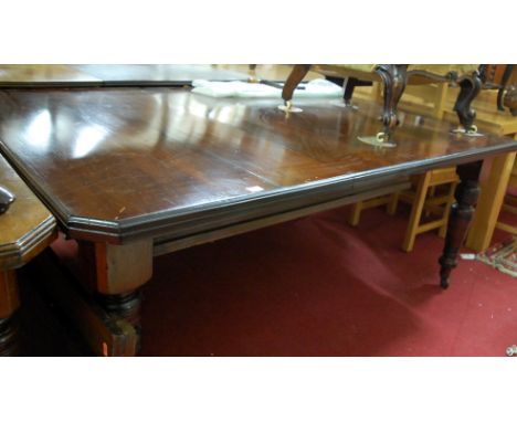 An Edwardian walnut extending dining table, having wind-out action, single extra drop-in leaf, with canted corners, on ring t