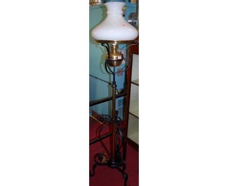 An Art Nouveau black painted wrought metal and brass freestanding oil lamp, having a telescopic action with milk glass shade