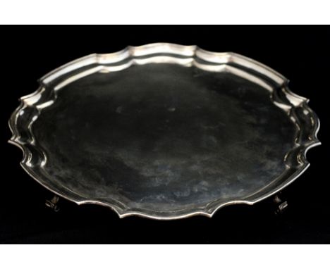 A George V silver salver, with Chippendale style border, atop four scroll form supports, hallmarks struck to the underside, s