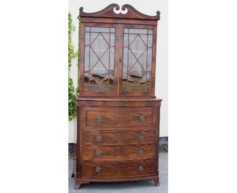 A George III mahogany secretaire bookcase, the upper section with a swan-neck pediment over two glazed doors enclosing multip