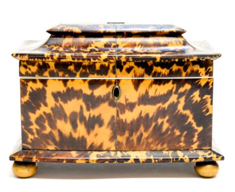 A Regency blonde tortoiseshell tea caddy, circa 1820, of sarcophagus form, silver wire inlay, opening to a fitted interior wi