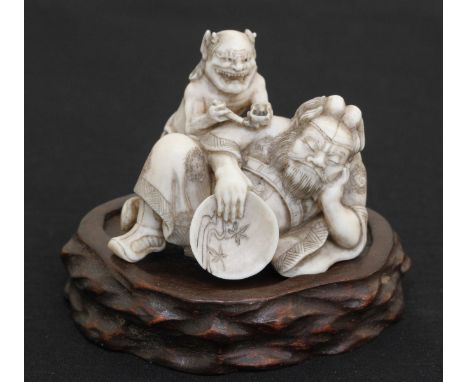 A finely modelled and carved Japanese Meiji period Ivory Netsuke-Okimono, carved as an ogre 'type' sleeping porcelain painter