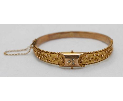 An early 20th C. 9ct gold hinged bangle bracelet, set to the top with three small aquamarines, and further decorated with rop