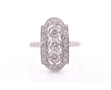 A diamond and platinum ring, the plaque-shaped ring centred with three round brilliant-cut diamonds within an elongated borde