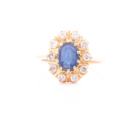 A sapphire and diamond cluster ring; the oval cut sapphire claw-mounted within a border of round brilliant diamonds set withi