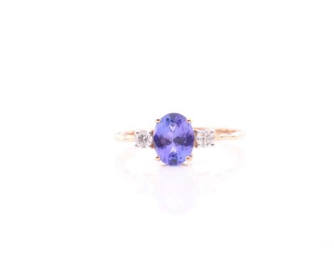 A 14ct yellow gold, tanzanite and diamond ring, set with a mixed oval-cut tanzanite measuring 8.5 x 6.6 mm, flanked with two 