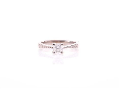 A single stone diamond ring; the round brilliant cut diamond in four claw mount, to seven stone diamond set shoulders and pla