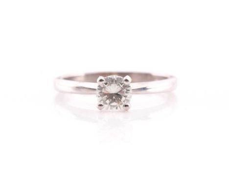 A single stone diamond ring, the round brilliant cut diamond in simple raised claw mount; to tapering shoulders and plain 18 