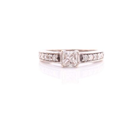 A single stone princess cut diamond ring; the princess cut diamond in four claw mount to seven stone diamond set shoulders. P