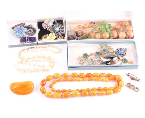 A small group of costume jewellery items to include an amber style (plastic) necklace, three silver and enamel brooches, furt