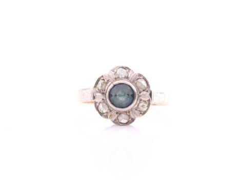 An early 20th century cluster ring; the blue/green circular centre stone within a foliate shade border of six mixed old cut s