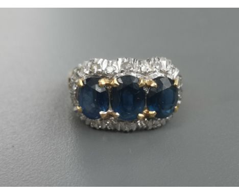 A three stone sapphire &amp; diamond cluster ring, the three claw set oval sapphires of total approximate weight 3 carats, wi