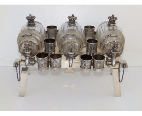 A Victorian crested silver tantalus of barrel &amp; stillage form, the three horizontally placed cut glass spirit barrels eac