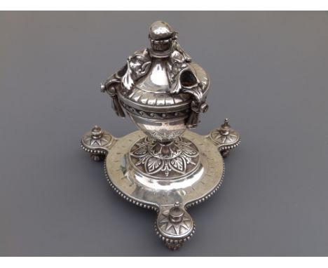 A 19thC silver plated table-top cigar lighter/stand, of urn form having three mask holders for cigars, on circular platform b