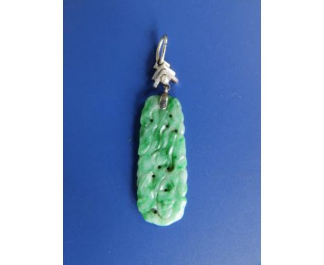 A green  jade pendant, of flat slightly tapering form, carved with fruiting foliage, the white metal mount set with a seed pe