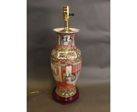 A Cantonese enamel style lamp and hardwood stand with decorative panels depicting figures in an interior and birds amongst fo