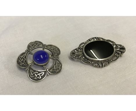 2 silver brooches set with stones. A Celtic design with a central blue cabochon stone and one set with marcasite and black on