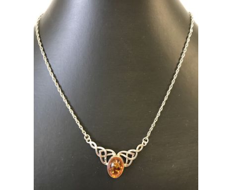 An amber & silver pendant in Celtic design. Boxed. 16 inch in length.