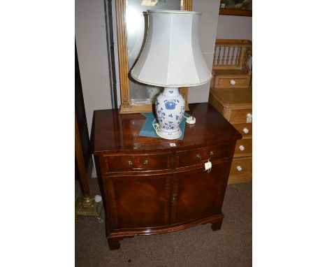 A reproduction mahogany serpentine front side cabinet, fitted two drawers and two cupboard doors, 74cms wide; together with a