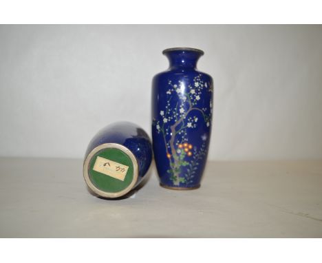 A pair of Japanese cloisonne enamel vases decorated with blossoming trees, birds in flight on a blue ground, retailer's label