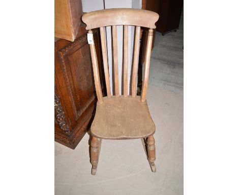 A stripped wood Windsor style rocking chair with solid seat.