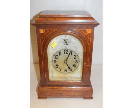 An Edwardian oak inlaid mantel clock, with engraved arabic dial.