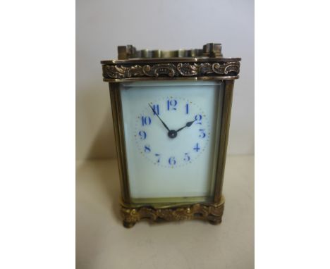 An 8 day carriage clock, brass decoration to top and bottom, enamel dial with blue numerals, 12cm tall, running with key, chi