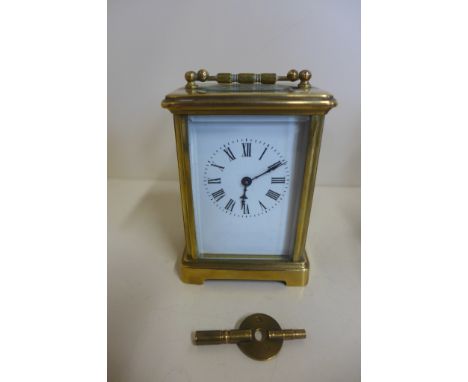 An 8 day carriage clock, 12cm tall, running with key, chip to one glass 