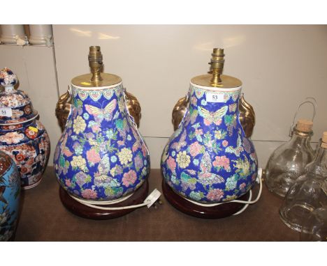 A pair of Oriental style ceramic table lamp bases with gilt rams head decoration on circular black bases