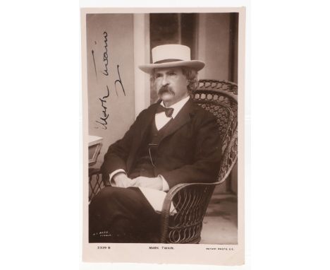 Mark Twain. A postcard photograph portrait, seated in cane chair, wearing a dark suit and white hat, signed upper left 'Mark 