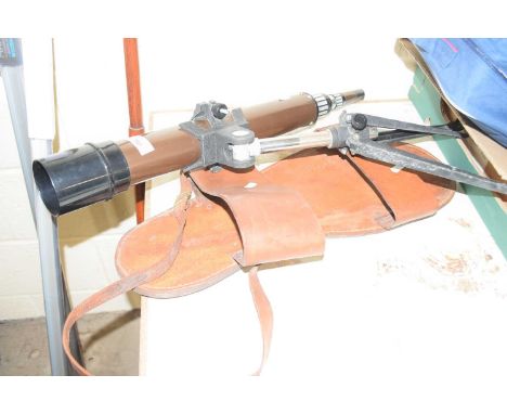 A giant leather sandle together with a small telescope and tripod
