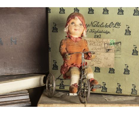 A Dean’s Rag Book Co girl doll riding a tricycle 1930s, with brown eyed printed face, blonde mohair curls, pink velvet dress,