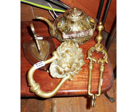 Ornate brass lion door knocker, ornate brass teapot, brass fire tongs and a shield-shaped wall hanging bracket