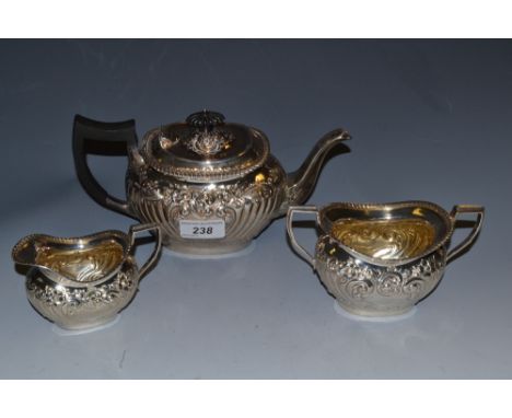 A late Victorian three piece bachelor's tea set, embossed with ornate foliage, gilt interior, the teapot with ebonised handle