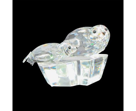 A clear crystal figurine of a seal and its child laying on a land mass. Black crystals are used to decorate the eyes and snou