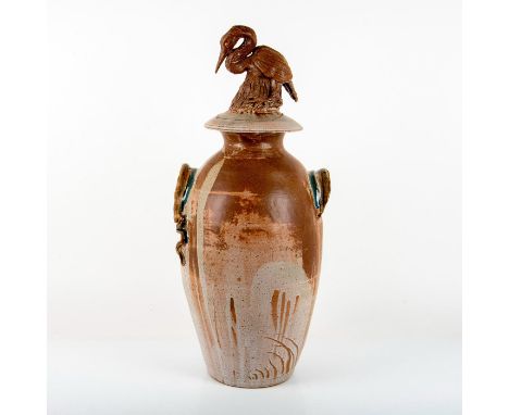 A beautiful ceramic covered urn with brown and gray glaze. A molded stork atop of the lid, and serpent handles. Artist signed