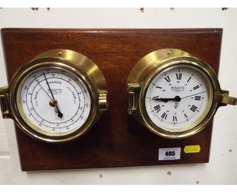 A bulkhead wall clock and barometer set on a mahogany plinth
