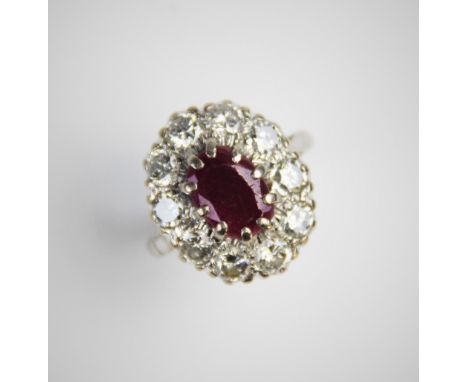 A ruby and diamond cluster ring, comprising a central oval mixed cut ruby measuring 11mm x 8mm, claw set to a surround of ten